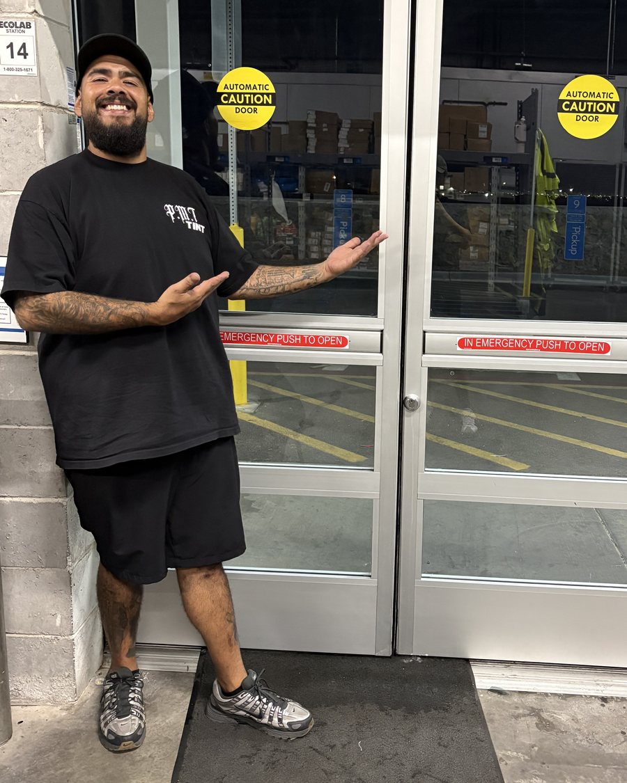 Marcos, owner of PMT Tint, with a freshly tinted storefront door in El Paso